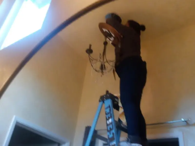 Electrician installing a chandelier in a Smith residence